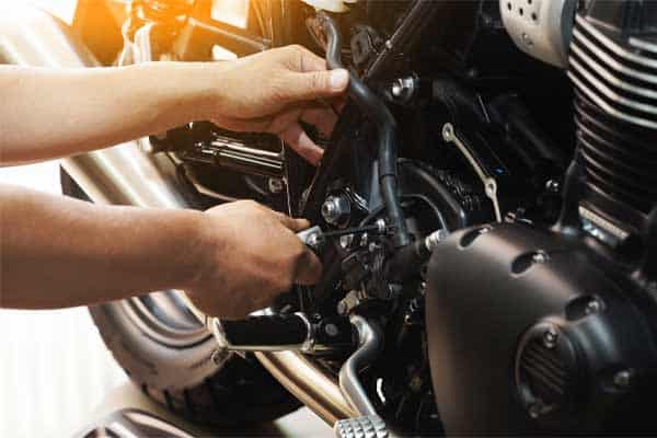 An image of a man performing maintenance on a motorcycle