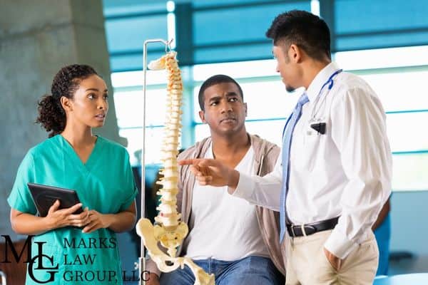 man consulting a doctor about his spine injury, Why are spinal injuries serious