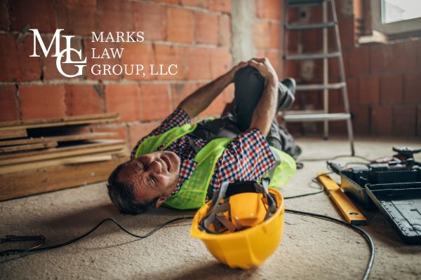 a man lying on the ground holding his knee after falling off a ladder on a construction site