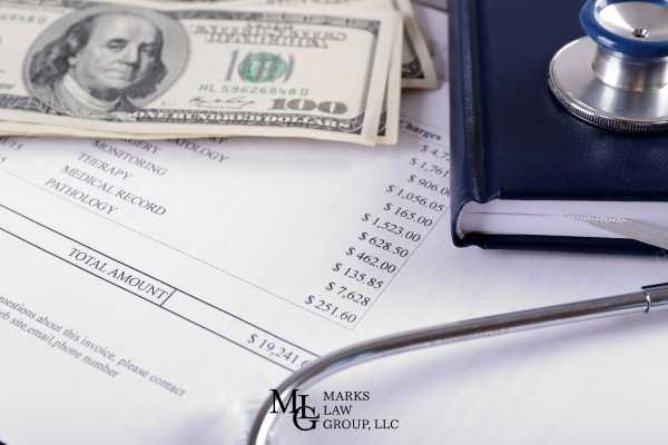 a medical billing statement, stethoscope, and money on a desk
